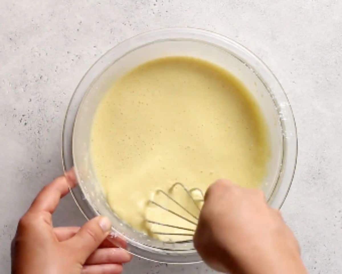 Whisking smooth blini batter in a glass mixing bowl
