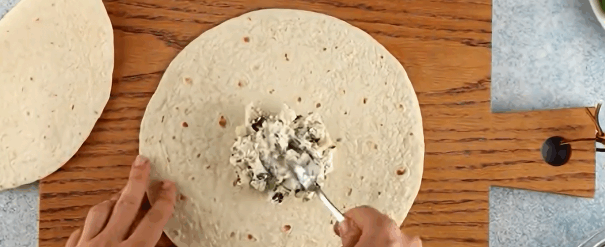 Spreading cream cheese mixture over tortilla.