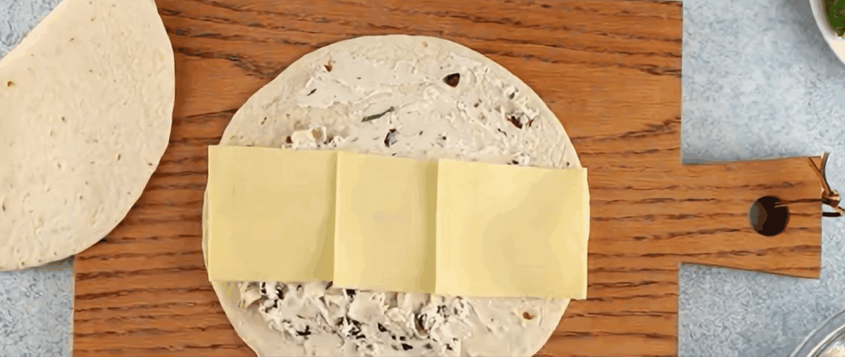 Topping the cream cheese mixture with slices of cheese.