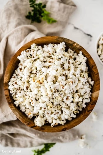 overhead of garlic bread popcorn in wooden bowl with brown napkin