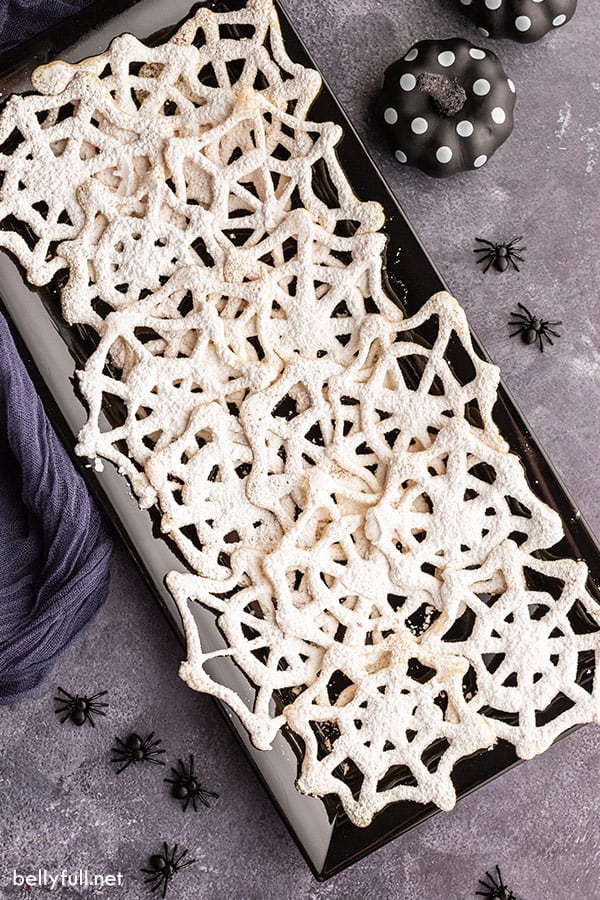 overhead of black serving tray filled with spiderweb halloween cookies