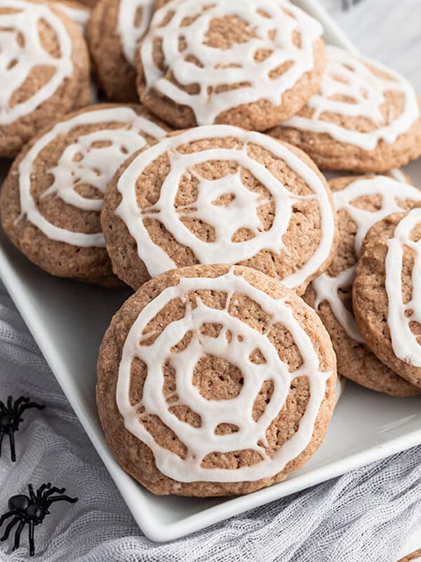 a white tray filled with chocolate sugar cookies with spiderweb icing