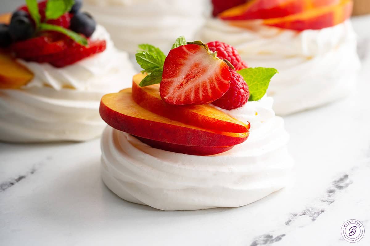 Pavlova with peaches, strawberries, raspberries, and fresh mint.