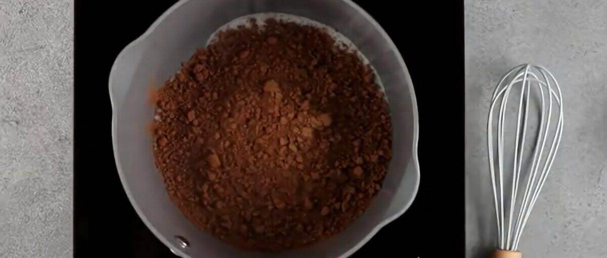 Cocoa powder and sugar in a pot with a whisk next to it. 