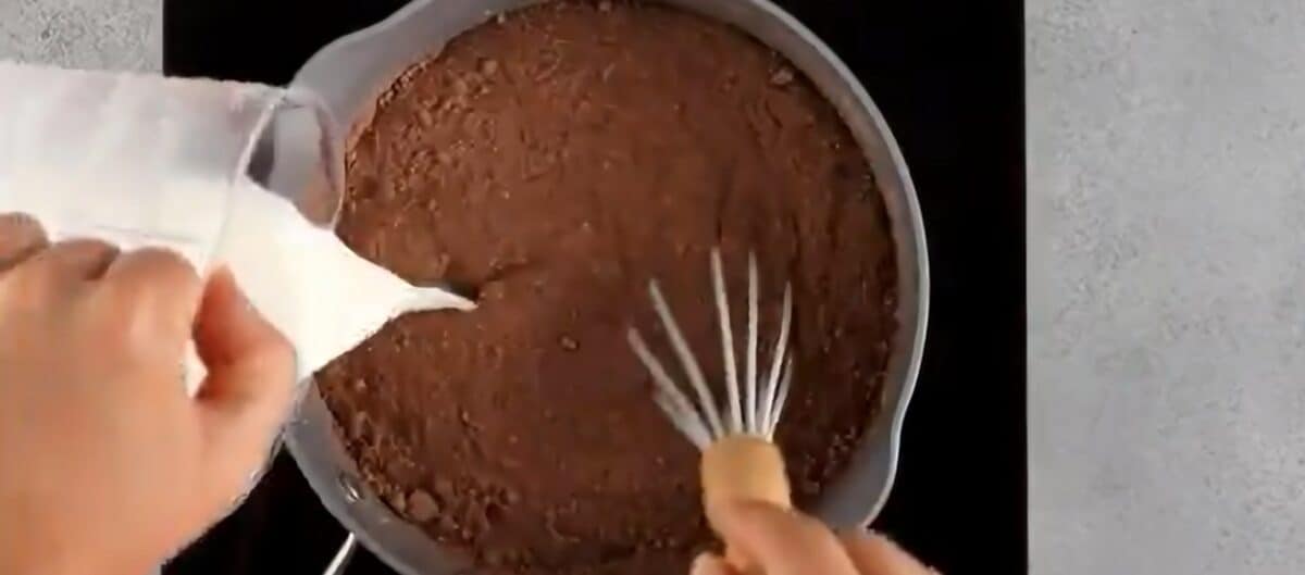 Whisking milk into the chocolate and sugar mixture.