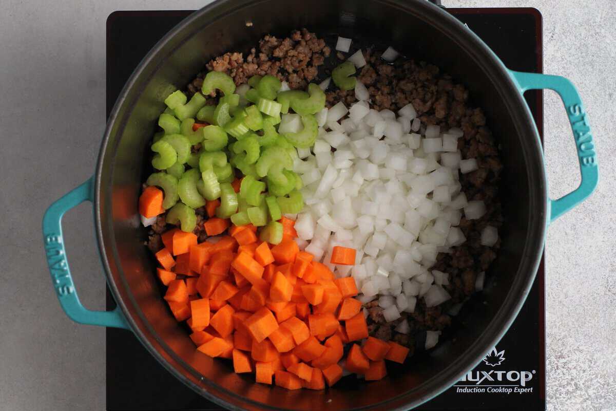 Adding onions, carrots and celery to the pot.