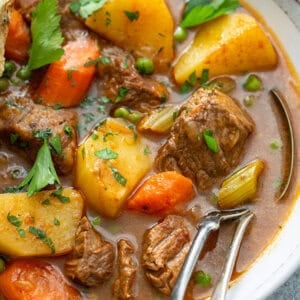close up of beef stew in bowl with fork and spoon