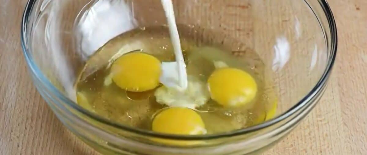 Pouring milk into a bowl with 3 eggs as part of the wet mixture to make baked oatmeal.
