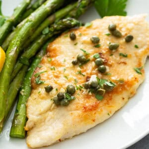 close up of chicken piccata on plate with roasted asparagus