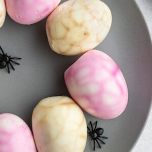 close up of spider web eggs on gray plate with plastic spiders