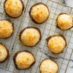 macaroons dipped in chocolate and crushed pistachios on cooling rack
