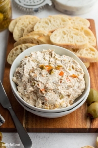 White bowl filled with olive spread and slice bread in the background