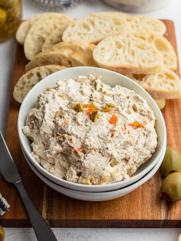 White bowl filled with olive spread and slice bread in the background