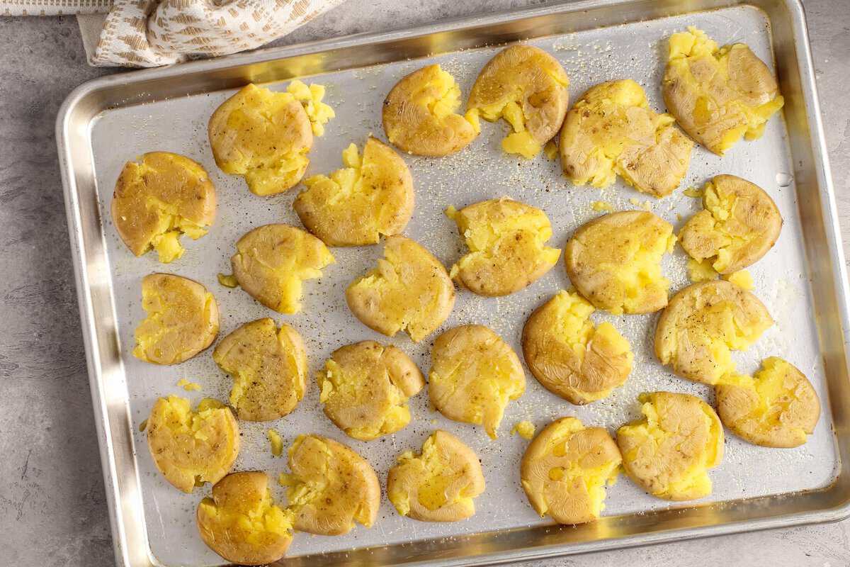 Smashed baby new potatoes on a baking sheet.
