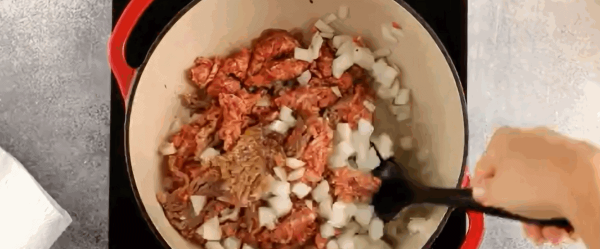 Adding pork and onions to the pot.