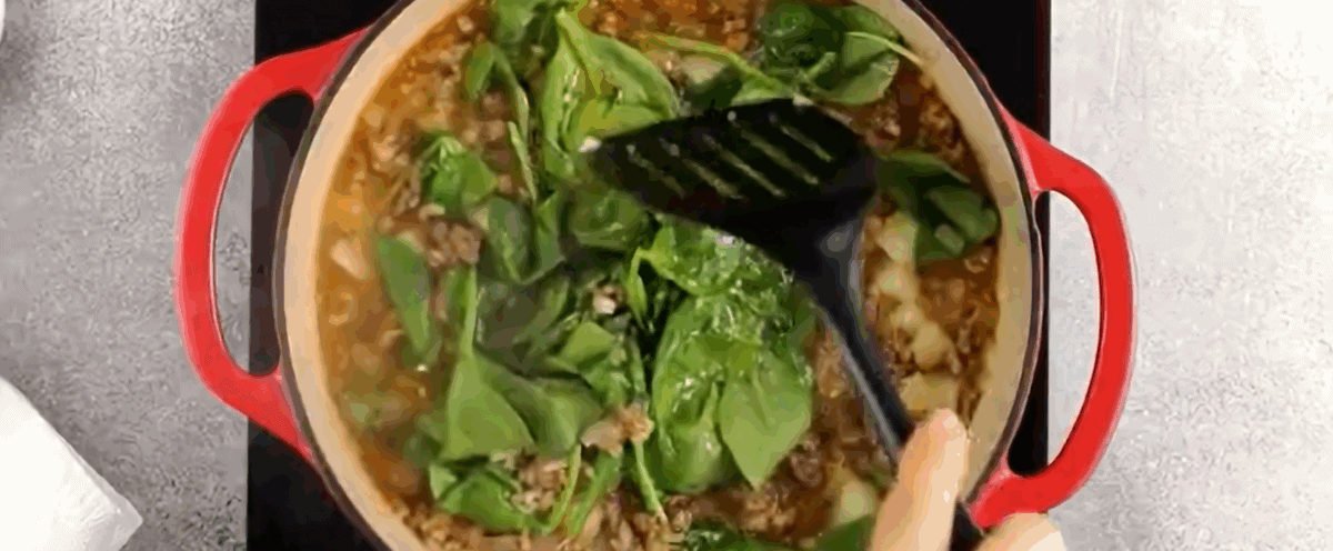 Adding spinach to the pot. 