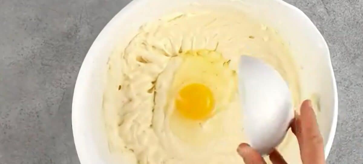 Adding eggs to the cream cheese mixture.