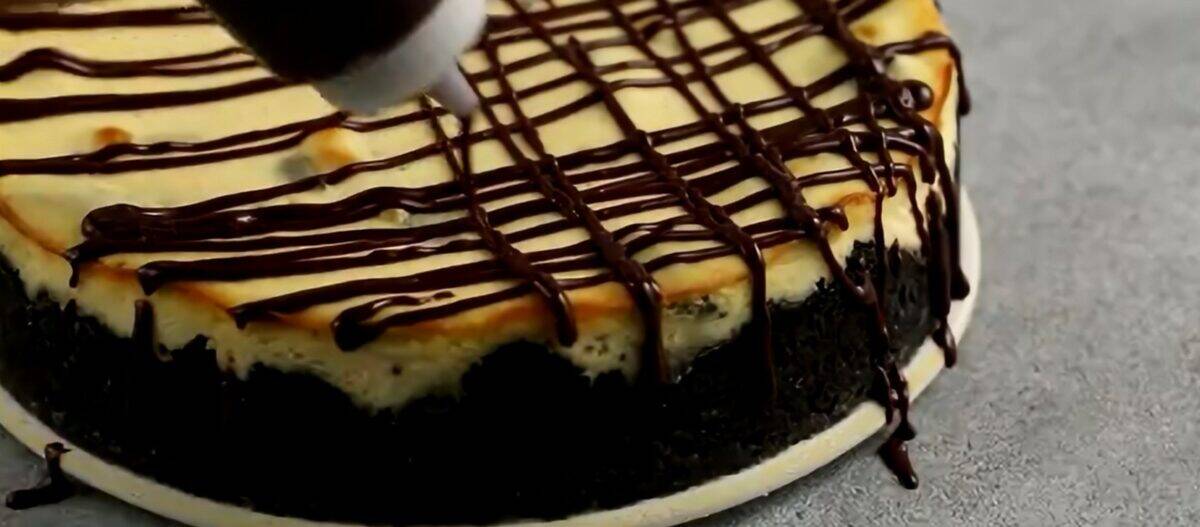 Drizzling chocolate ganache over the cooled cheesecake.