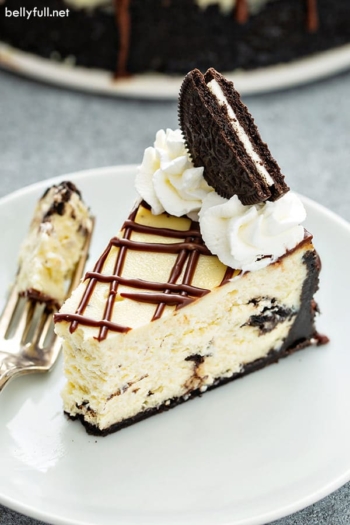 cheesecake with with bite taken, garnished with an Oreo and whipped cream