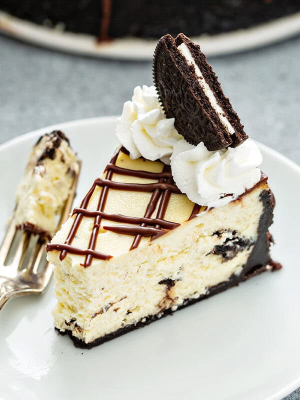 cheesecake with with bite taken, garnished with an Oreo and whipped cream