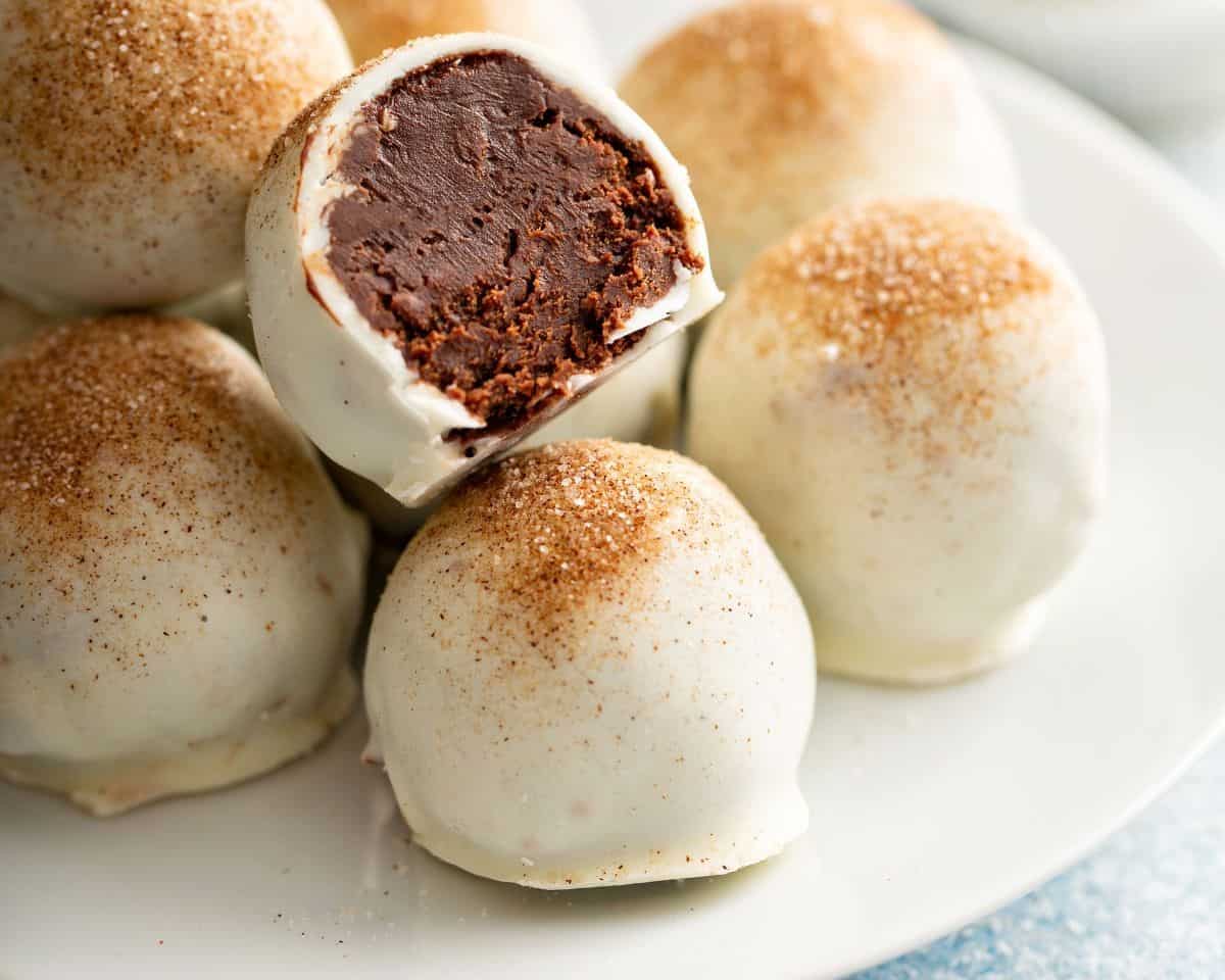 Bailey's Chocolate Truffles on a white plate with one truffle with a bite taken out of it.