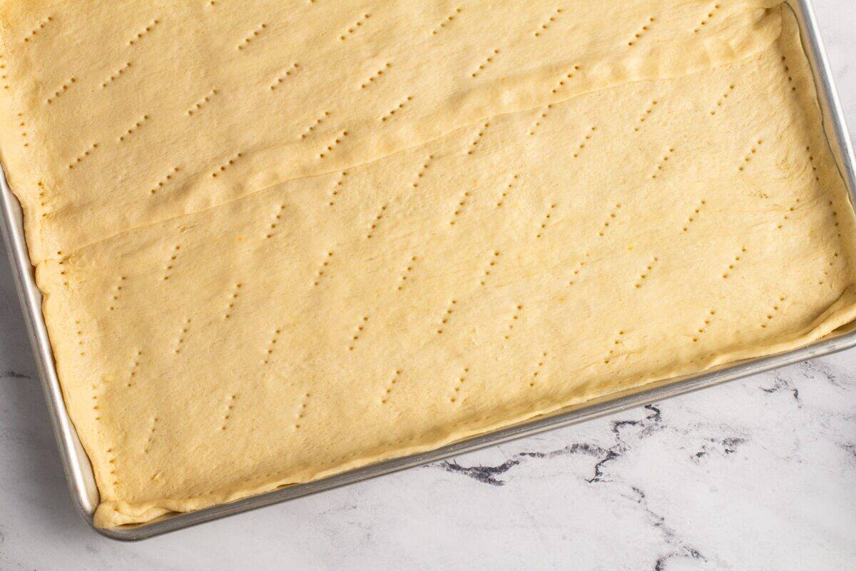 Poking holes in the rolled out dough on a cookie sheet.