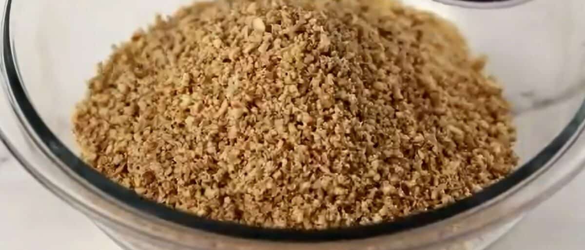 Cookie crumbs and processed pecans in a glass bowl.