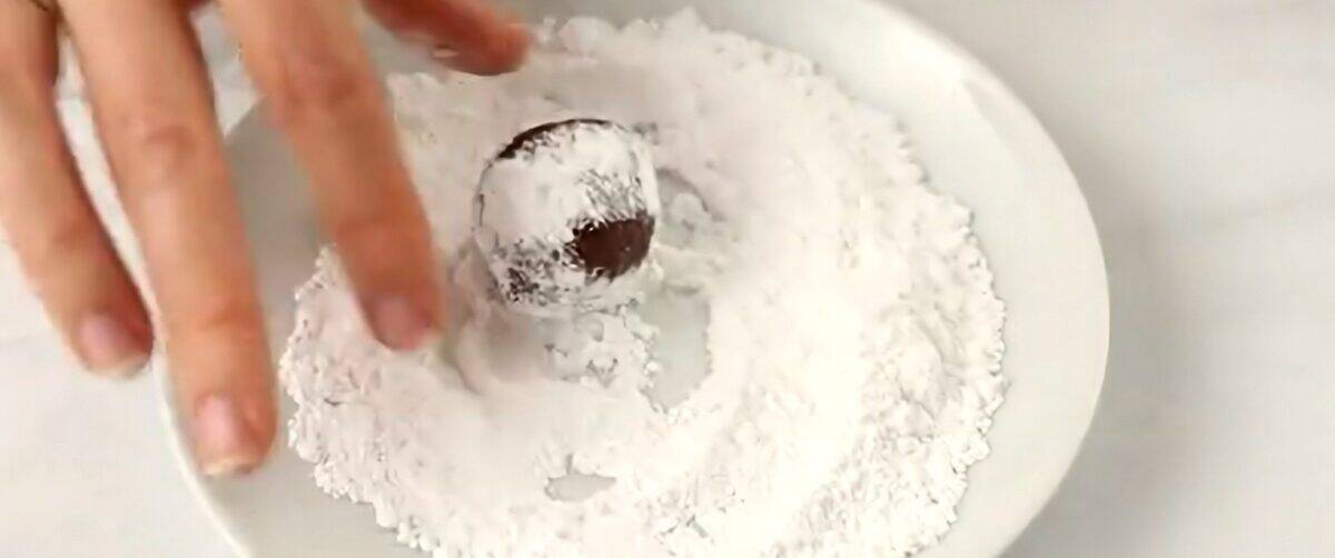 Rolling the rum ball in powdered sugar.