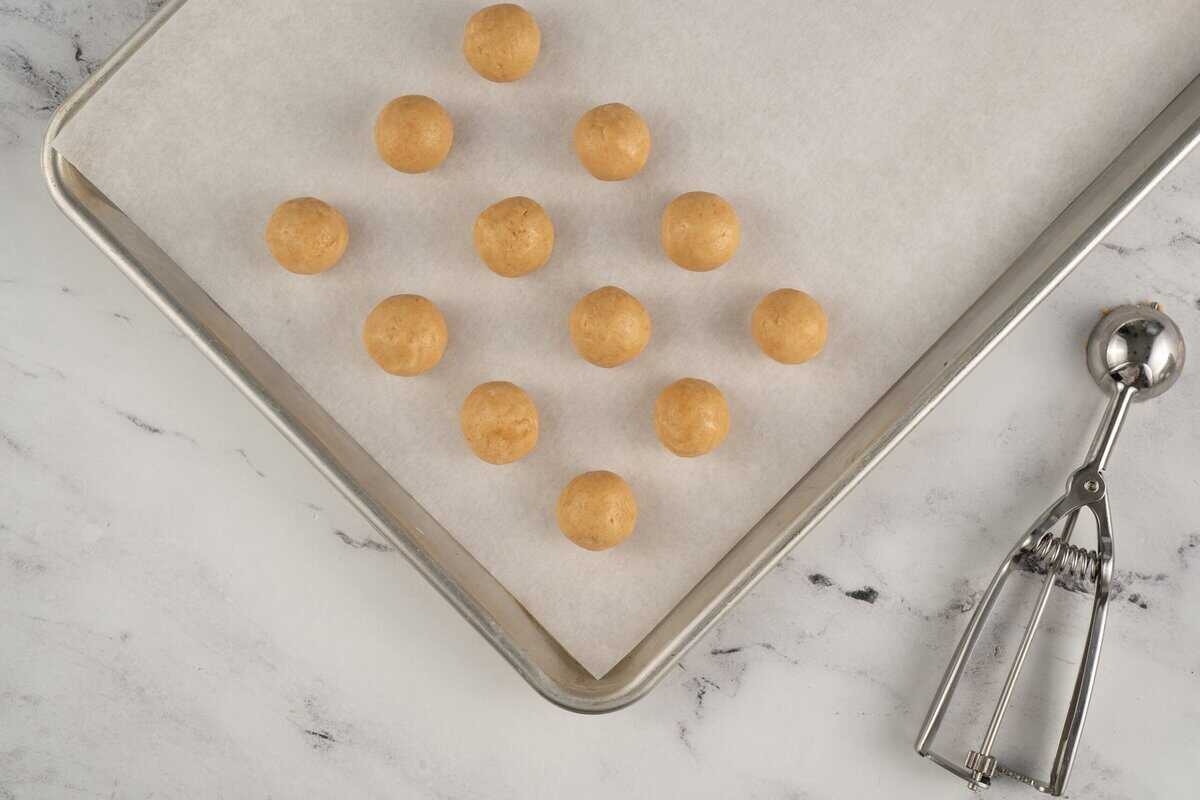 Sugar cookie dough balls on a parchment lined cookie sheet.