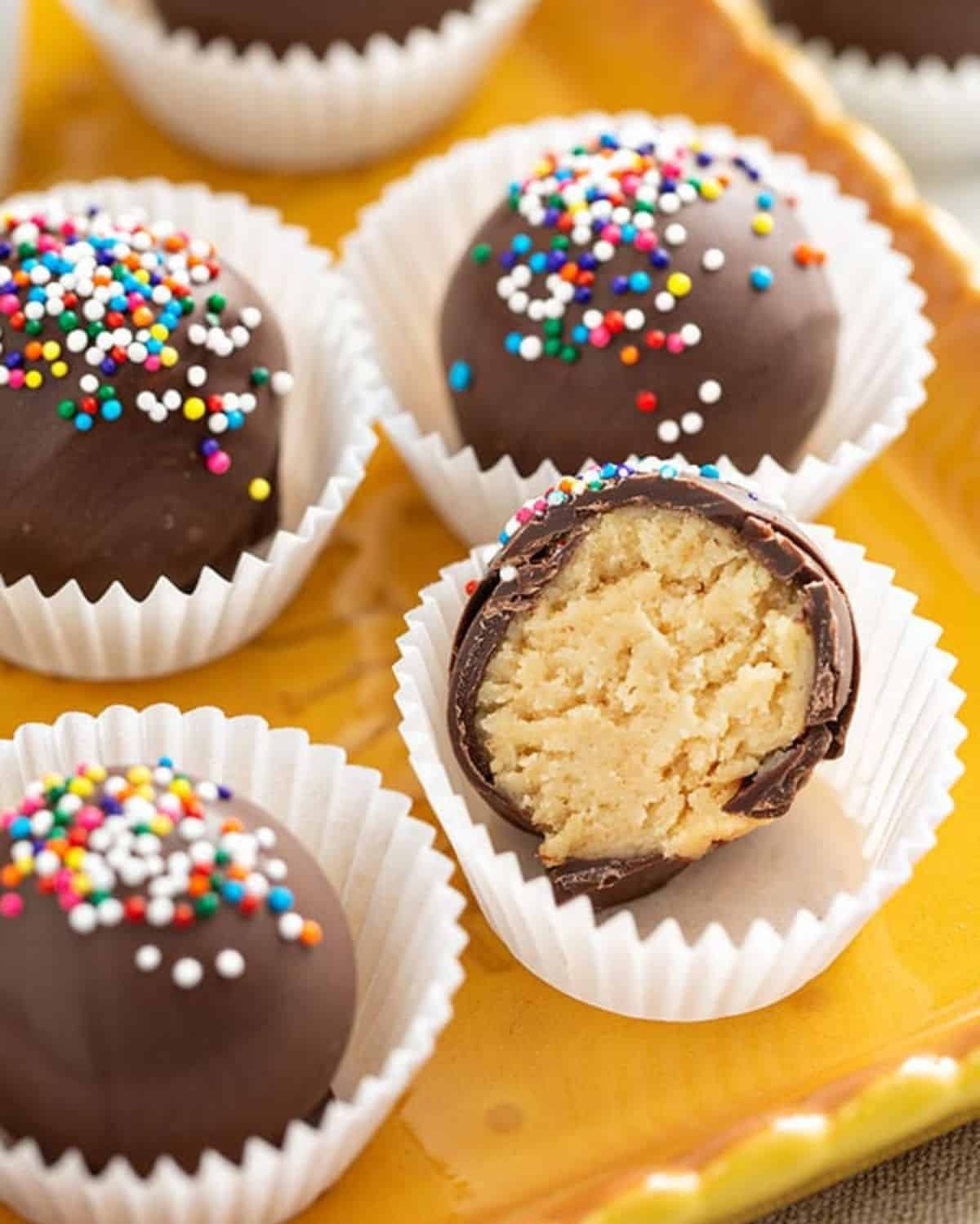 Sugar cookie truffles on a tray with one cut open to show the inside.