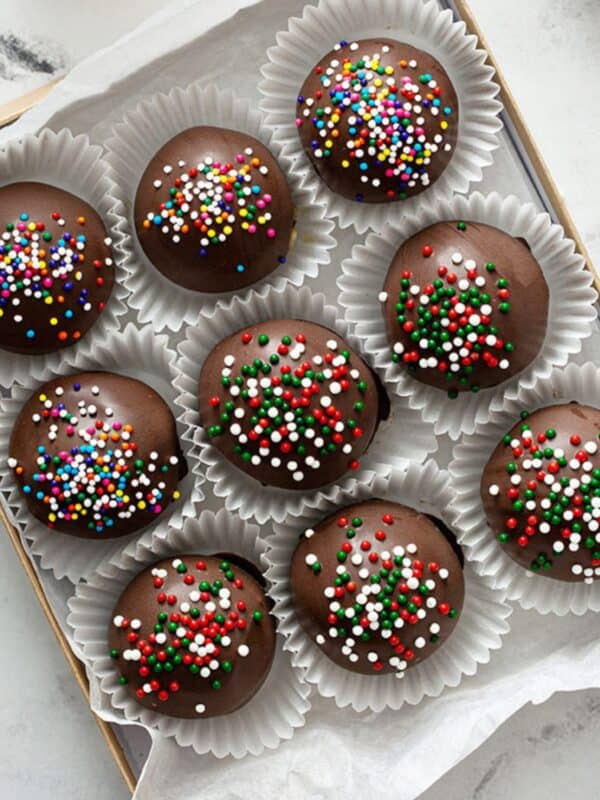 Sugar Cookie Truffles in paper cups on a parchment lined tray.