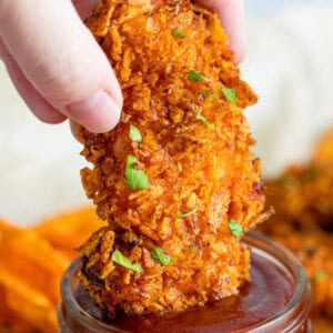 air fryer chicken tenders being dipped into BBQ sauce