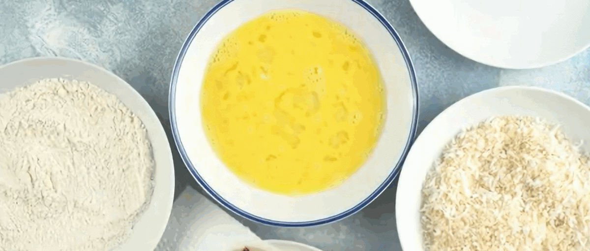 Three bowls for dredging the shrimp; one with flour, one with egg and one with coconut and breadcrumb mixture.