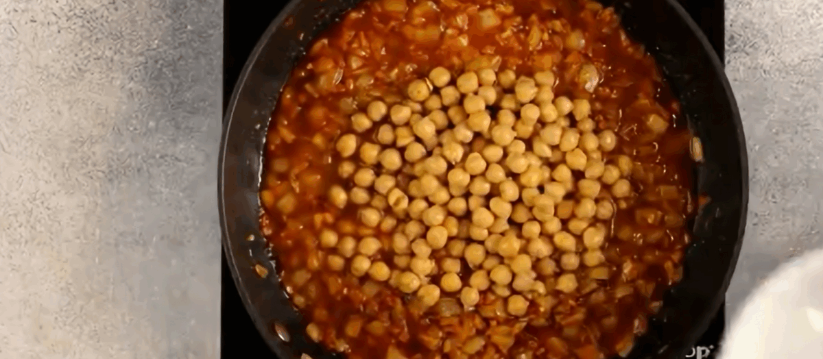 Adding chickpeas to the skillet.
