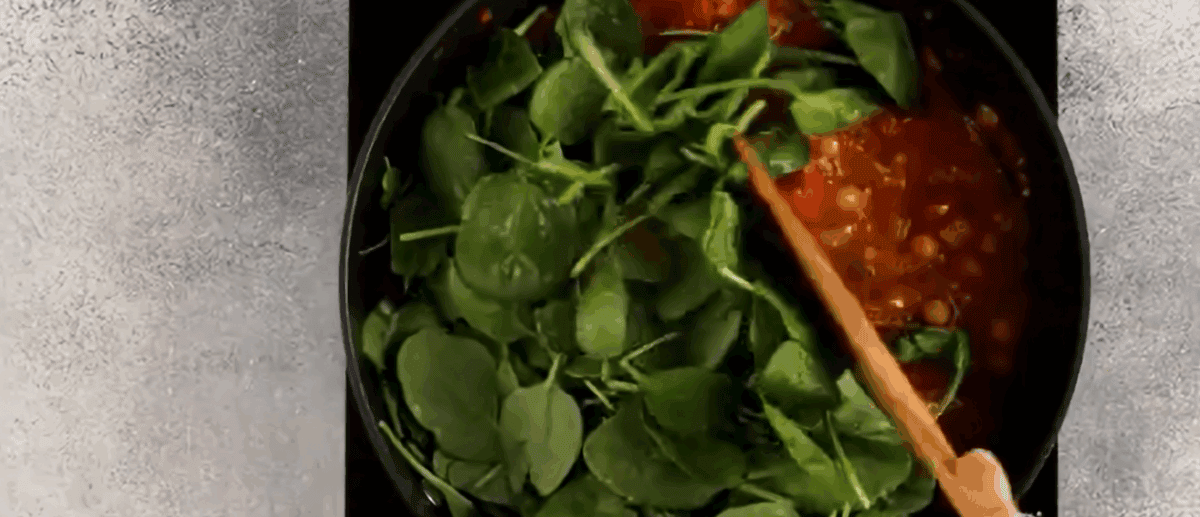 Stirring spinach into the chickpea curry.