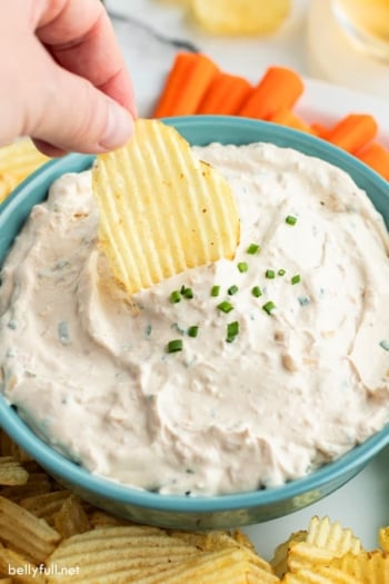 wavy potato chip being dunked into French Onion Dip