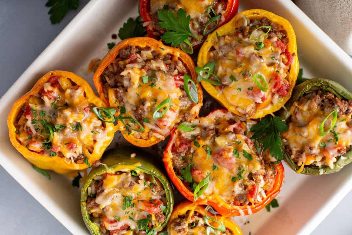Baked stuffed peppers with melted cheese, garnished with fresh parsley and sliced green onions