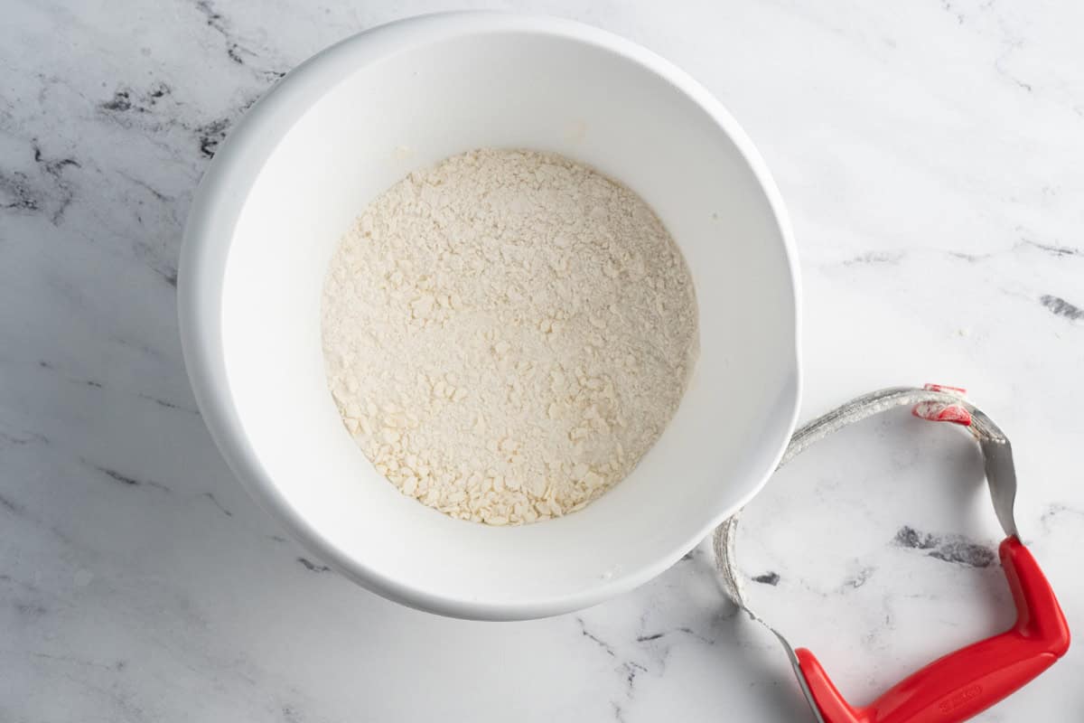 A bowl of the dry ingredients and a pastry cutter.