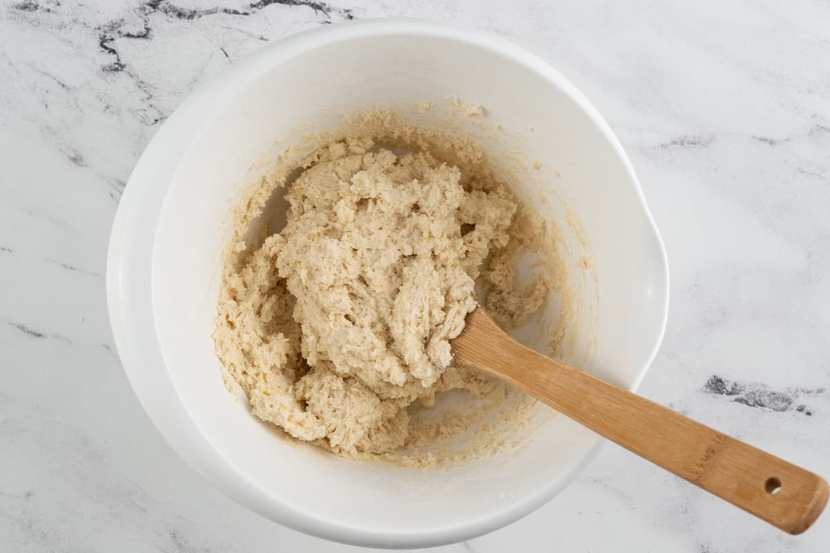 Wet scone dough in a white bowl with a wooden spoon.