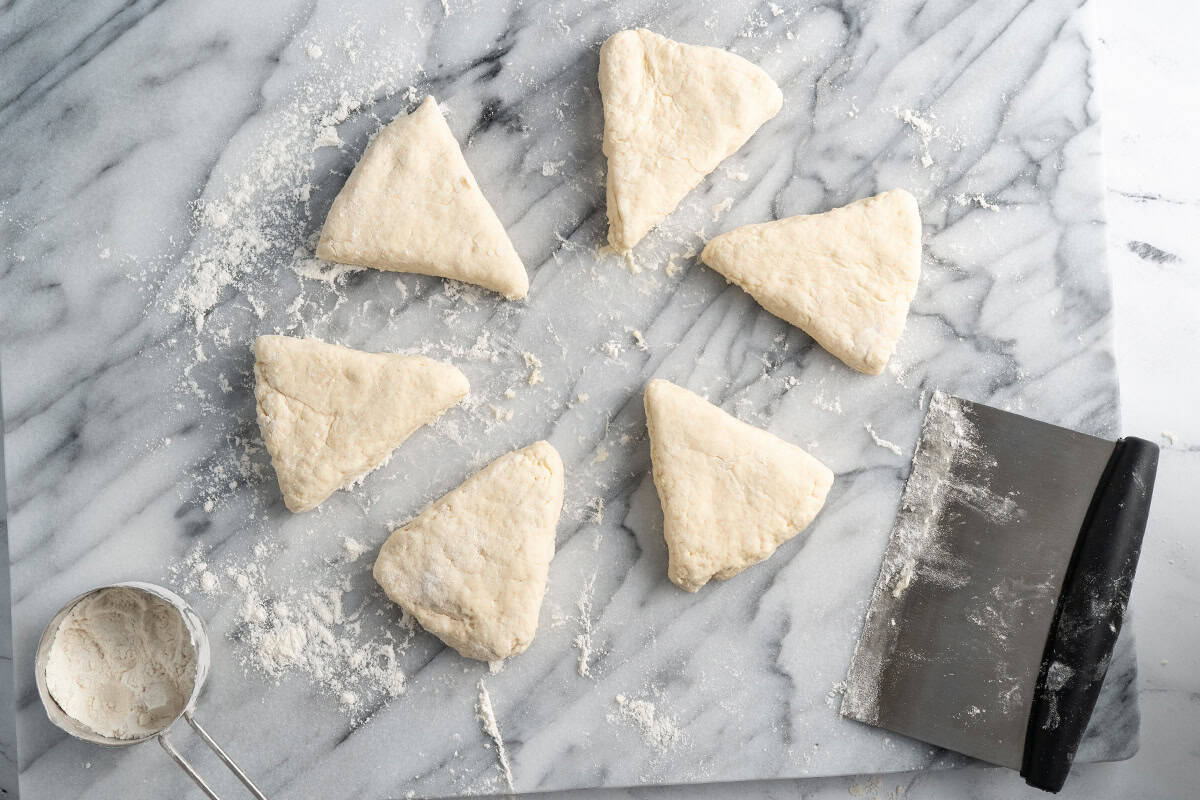 Dough triangles on a floured counter with a bench scraper.
