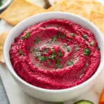 side angle homemade beet hummus on white serving bowl