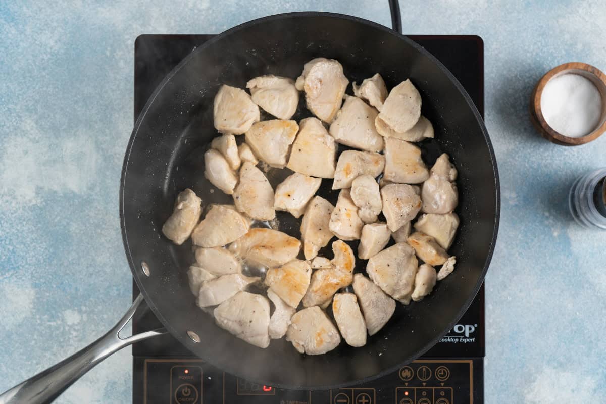 Cooking cubes of chicken in a skillet.