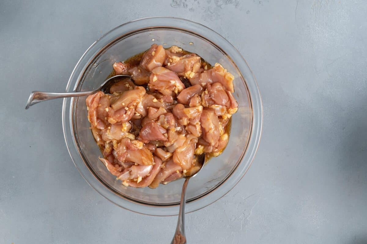 Chicken marinating in a glass bowl.