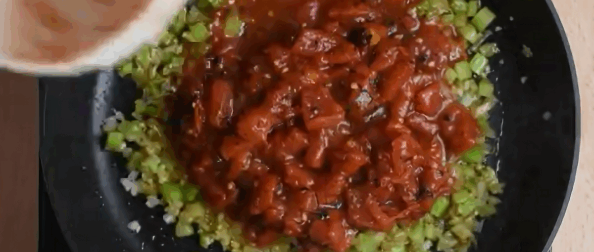 Adding diced tomatoes to the skillet with onions and celery. 
