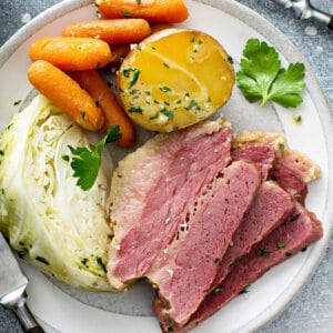 overhead 3 slices corned beef with vegetables on white plate