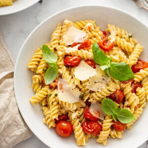 rotini pasta with cherry tomatoes and shaved parmesan in white bowl