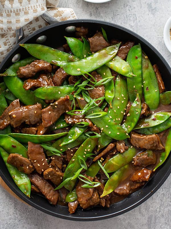 overhead beef stir fry with snow peas in skillet