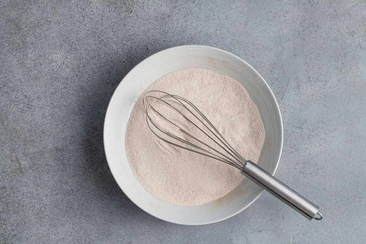 Cinnamon sugar mix in a white bowl with a whisk.