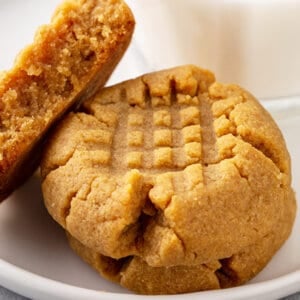 3 peanut butter cookies on white plate, 2 whole, 1 split