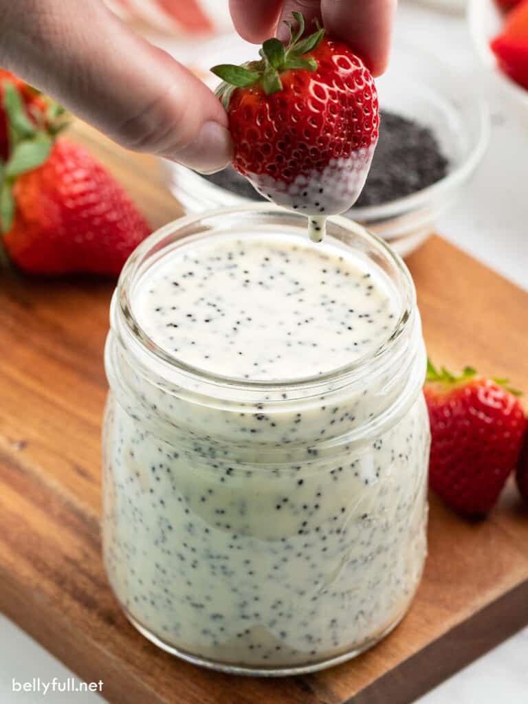 strawberry being dipped in poppy seed dressing